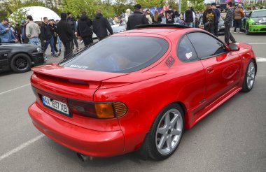 Canlı kırmızı Toyota Celica coupe, ön far, düşük profil ve sportif estetik 90 'ların Japon iç pazarındaki JDM performansının özünü mükemmel bir şekilde yansıtıyor.