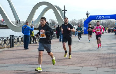 Group of runners participate in a city road race along a riverfront promenade showcasing fitness, energy, and outdoor sport