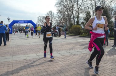 Bir park koşu etkinliği sırasında koşucuların yer aldığı dinamik açık hava yarış sahnesi, enerji yakalama, zindelik ve topluluk