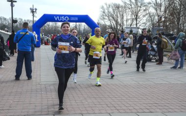 Bir park koşu etkinliği sırasında koşucuların yer aldığı dinamik açık hava yarış sahnesi, enerji yakalama, zindelik ve topluluk
