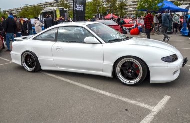 Beyaz Mazda MX-6, gösterişli, aerodinamik tasarımı ve rafine sürüş dinamikleriyle tanınan önden çekişli bir spor coupe.