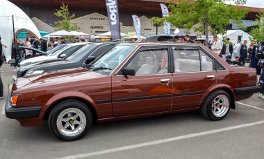 Kahverengi Toyota Carina, geleneksel mühendislik ve 1980 'lerin kama tasarımı dengesi açısından büyük saygı görüyor.