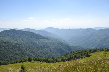 Yuvarlanan yeşil dağlar ve ormanlık vadiler parlak mavi bir gökyüzünün altında yükseliyor. Huzurlu, geniş bir manzara, keşfi, doğayı ve açık hava macerasını barışçıl ve manzaralı bir ortama davet eder. Karpatlar