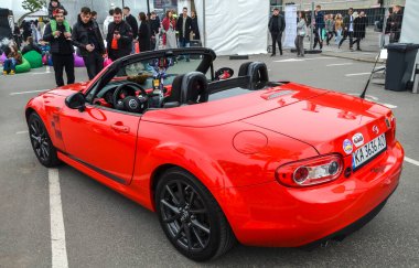 Canlı kırmızı Mazda MX-5 Miata otomotiv kültüründe simgesel yol gösterici olarak anılır, zamansız, dengeli tasarımı ve saf sürüş deneyimiyle ünlüdür.