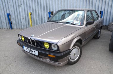 Bej rengi BMW (E30), keskin kullanım, ikonik köpekbalığı burnu tasarımı ve sürücü-merkezli ergonomik ile 3 Serisi itibarını pekiştirmesiyle yaygın olarak ünlenmiştir.