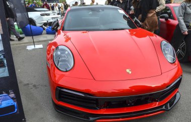 Siyah çatılı, kırmızı Porsche 911. Açık hava etkinliğinde agresif bir ön ayırıcı parlıyor. Alman mühendisliğinin gerçek bir başyapıtı.