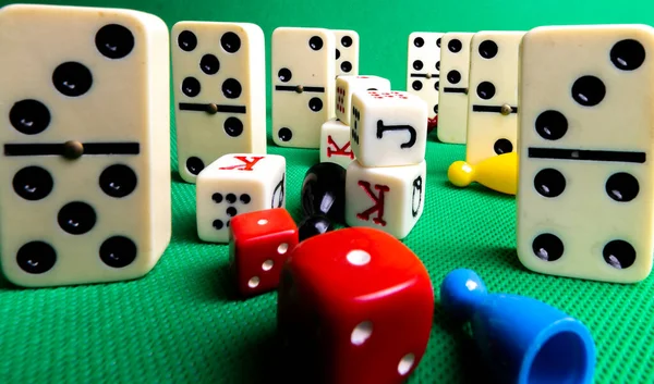 Composition on green background of board games, dice, dominoes, cards and ludo.