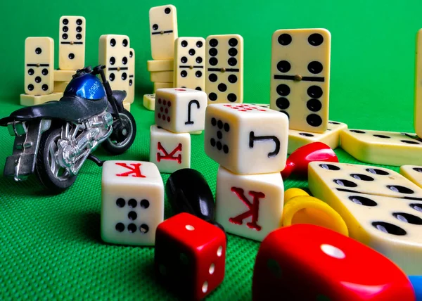 Composition on green background of board games, dice, dominoes, cards and ludo.