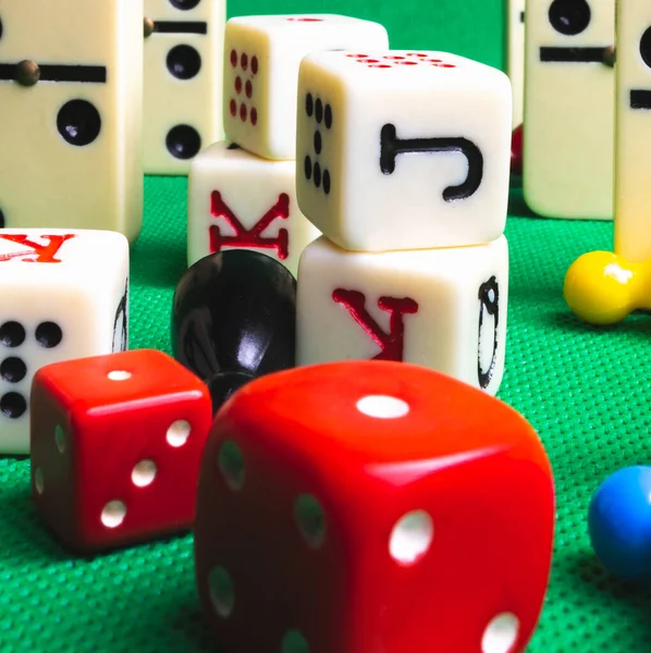 Composition on green background of board games, dice, dominoes, cards and ludo.