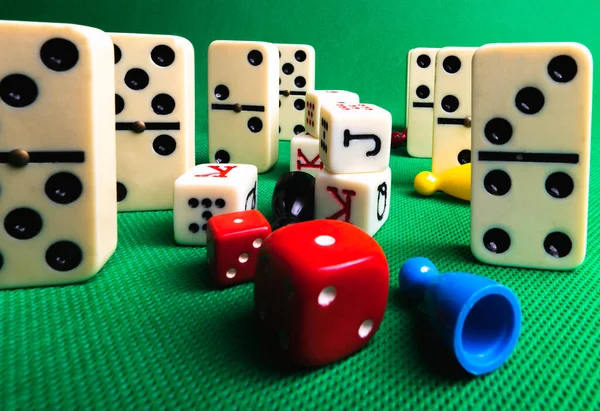 Composition on green background of board games, dice, dominoes, cards and ludo.