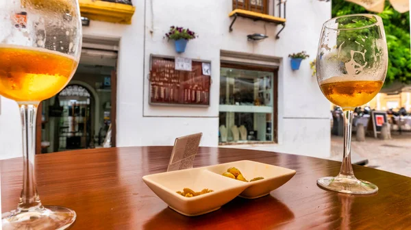 Scene of table in bar terrace with beers and plate of olives, tourist area in Cordoba.