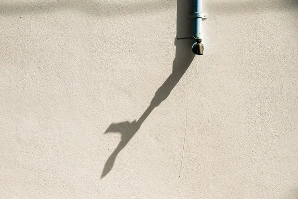 Shadow of a faucet on a white wall. Royalty Free Stock Images