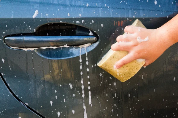 Mano femenina con esponja amarilla lavado coche — Foto de Stock