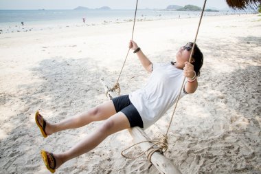 Salıncakta Cennet Adası tropik sahilde oturan kız