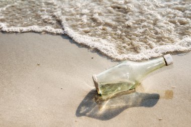 Boş cam şişe kıyıya vurmuş bir plajda çöp, çöp b olarak