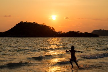 Mutlu çocuk sahilde günbatımı anda oynamak