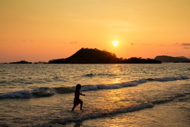 Mutlu çocuk sahilde günbatımı anda oynamak