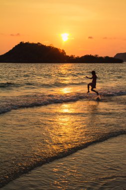 Mutlu çocuk sahilde günbatımı anda oynamak
