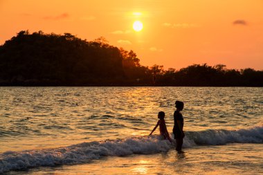 Anne ve kızı sahilde günbatımı anda oynamak.