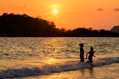Anne ve kızı sahilde günbatımı anda oynamak.