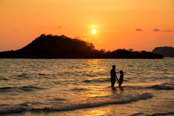 Anne ve kızı sahilde günbatımı anda oynamak.