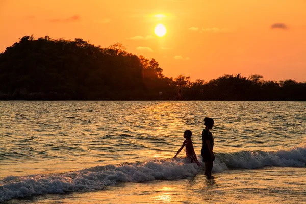 Anne ve kızı sahilde günbatımı anda oynamak.