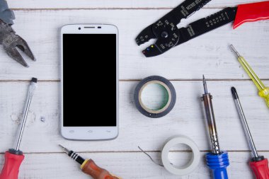 Beyaz ahşap zemin üzerinde smartphone ve donanım onarım.