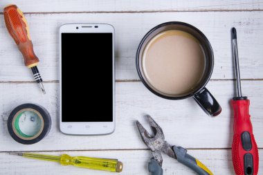 Beyaz ahşap onarım smartphone, kahve fincanı ve ekipman 
