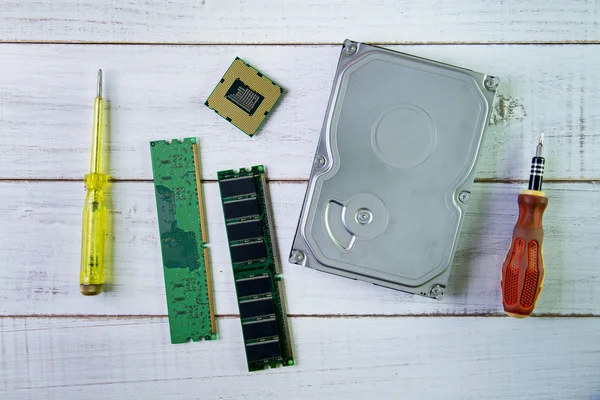 Destornilladores, chip de CPU y un disco duro en la parte posterior de madera blanca —  Fotos de Stock