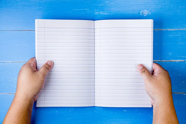 Libro aperto a mano sullo sfondo di legno blu . — Foto Stock