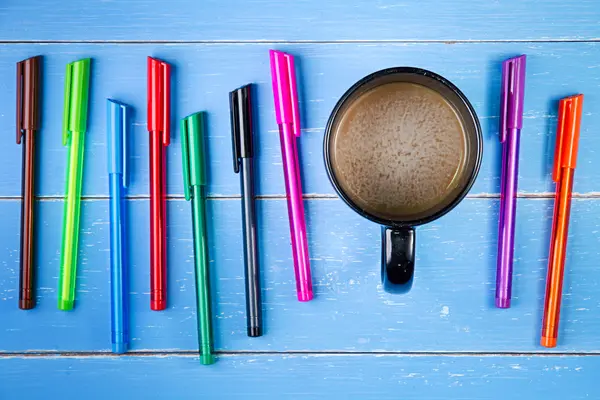 Copo de café e caneta de cor no fundo de madeira azul — Fotografia de Stock