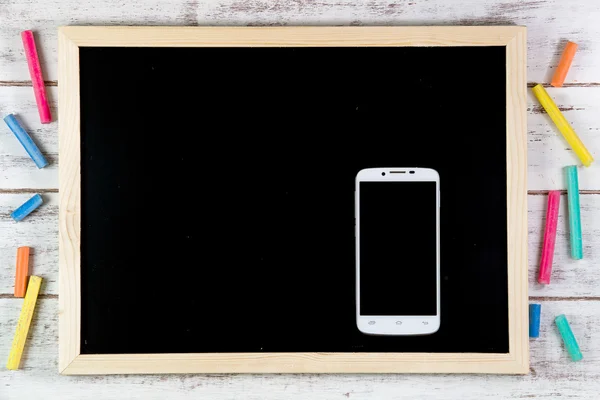 Blank blackboard and smart phone on wooden table.Template mock u
