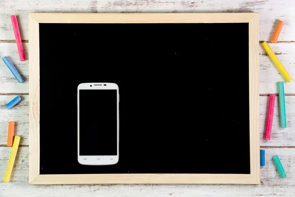 Blank blackboard and smart phone on wooden table.Template mock u