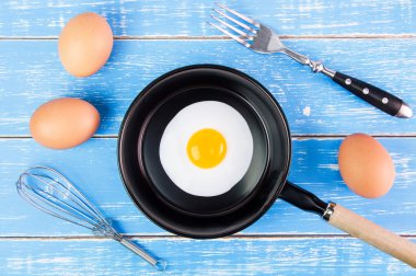 Mavi ahşap masa, üst kolu ile küçük tavada kızarmış yumurta vie