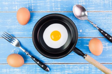 Mavi ahşap masa, üst kolu ile küçük tavada kızarmış yumurta vie