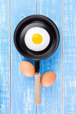 Mavi ahşap masa, üst kolu ile küçük tavada kızarmış yumurta vie