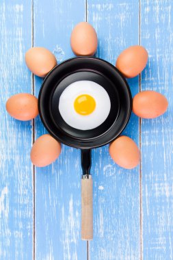 Mavi ahşap masa, üst kolu ile küçük tavada kızarmış yumurta vie