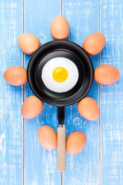 Mavi ahşap masa, üst kolu ile küçük tavada kızarmış yumurta vie