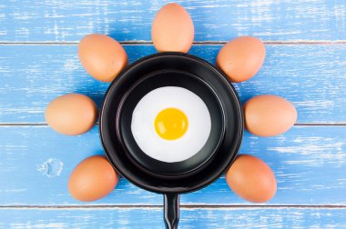 Mavi ahşap masa, üst kolu ile küçük tavada kızarmış yumurta vie