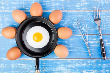 Mavi ahşap masa, üst kolu ile küçük tavada kızarmış yumurta vie