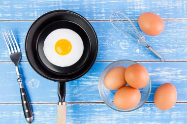 Mavi ahşap masa, üst kolu ile küçük tavada kızarmış yumurta vie