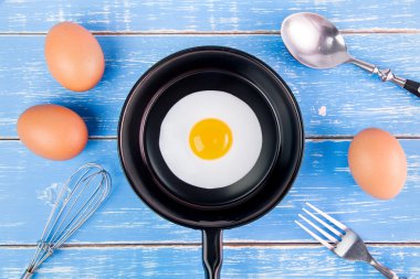 Mavi ahşap masa, üst kolu ile küçük tavada kızarmış yumurta vie