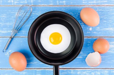 Mavi ahşap masa, üst kolu ile küçük tavada kızarmış yumurta vie