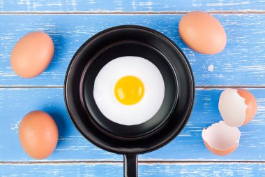 Mavi ahşap masa, üst kolu ile küçük tavada kızarmış yumurta vie