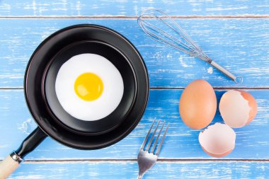 Mavi ahşap masa, üst kolu ile küçük tavada kızarmış yumurta vie