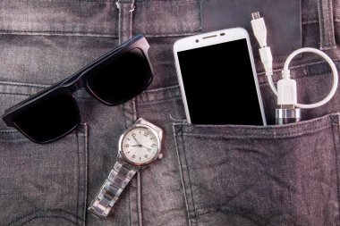 Smartphone, güneş gözlüğü, taşınabilir pil ve kot pantolon geri nöbette