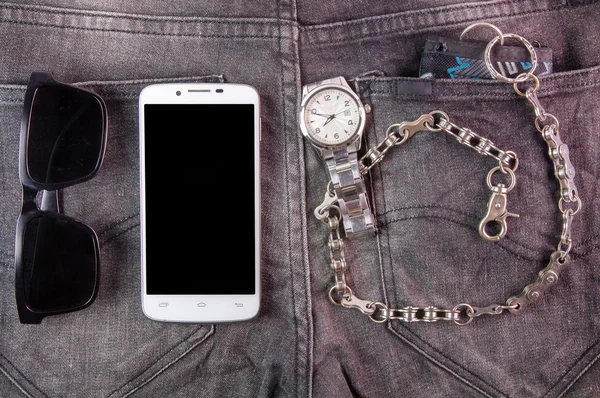 Smart phone, sunglasses, watch and wallet on jeans background