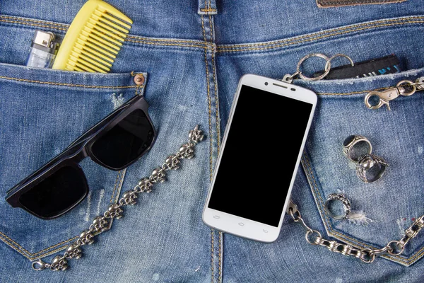 Smartphone, bracelet, sunglasses and Ring on jeans background