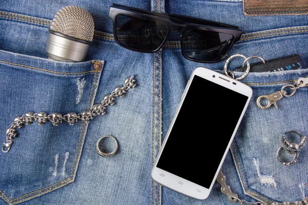 Smartphone, bracelet, Ring, sunglasses and microphone on jeans b