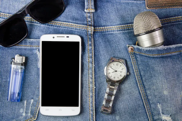 Smartphone, óculos de sol, relógio e microfone em fundo jeans — Fotografia de Stock